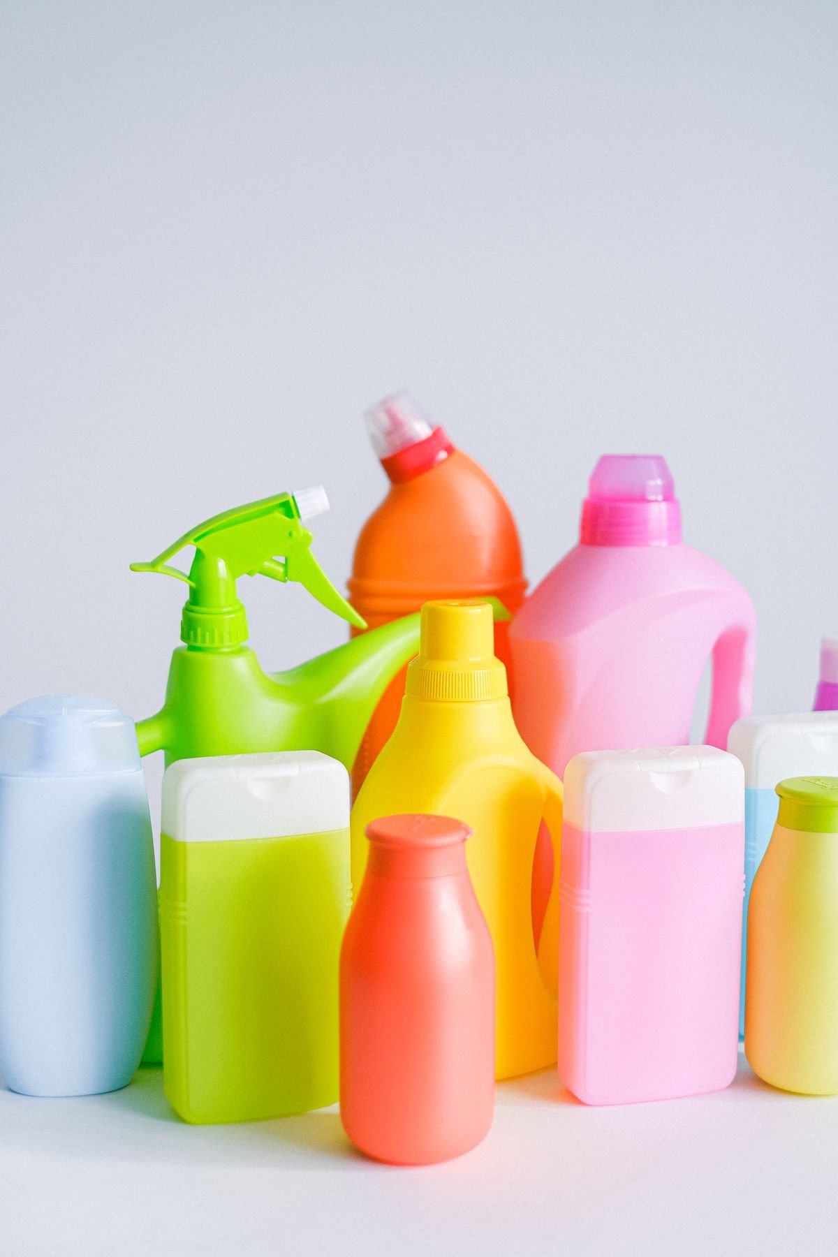 A group of colorful plastic cleaning product bottles, including a spray bottle